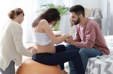 A birth Doula assisting a woman during labor and pregnancy, alongside the woman's partner.