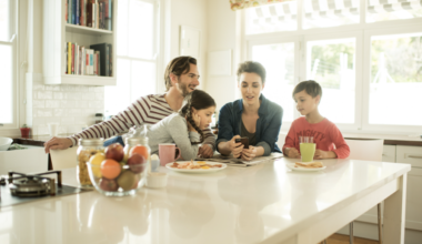 Parents and their children looking at a phone together; as to depict how to stay connected to our phones without disconnecting from our children.
