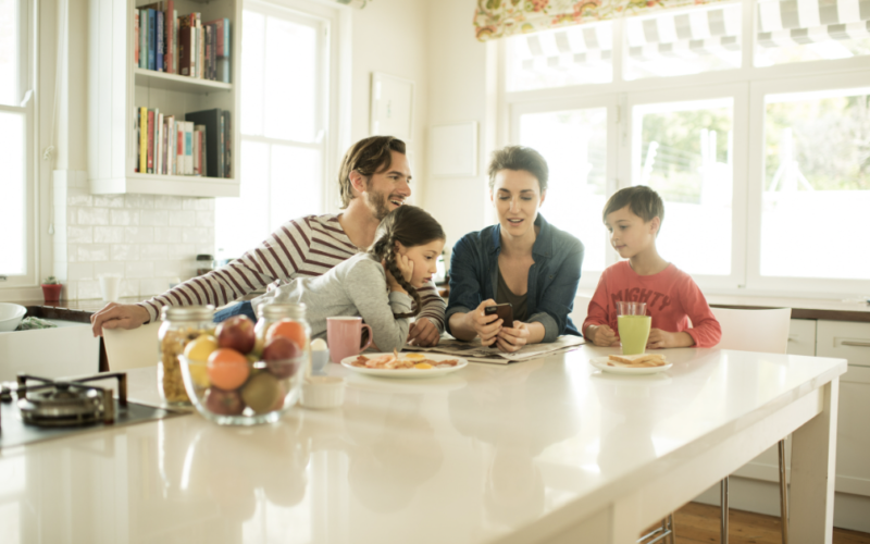 Parents and their children looking at a phone together; as to depict how to stay connected to our phones without disconnecting from our children.
